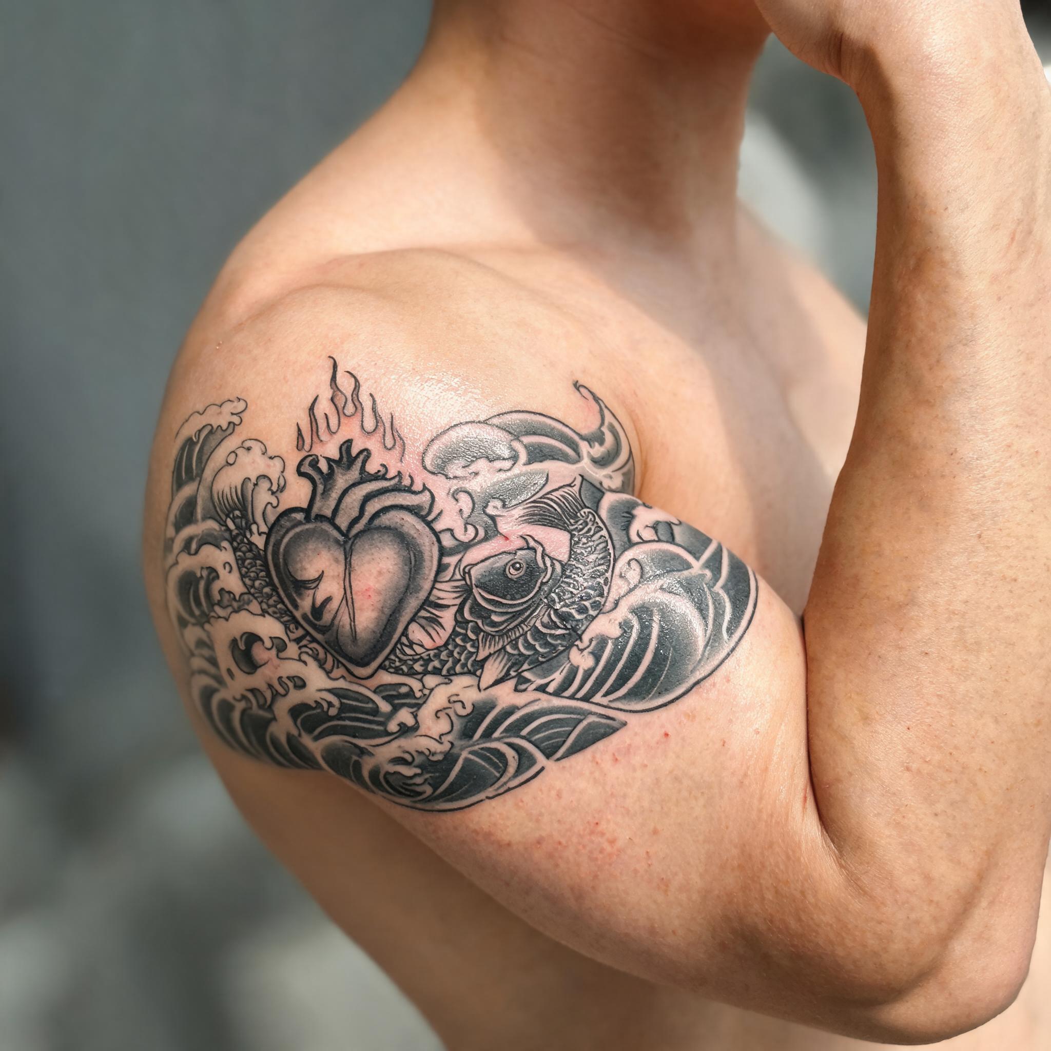 Japanese Irezumi sacred heart tattoo images on an inner bicep, black and grey ink, photographed on skin against a neutral background.