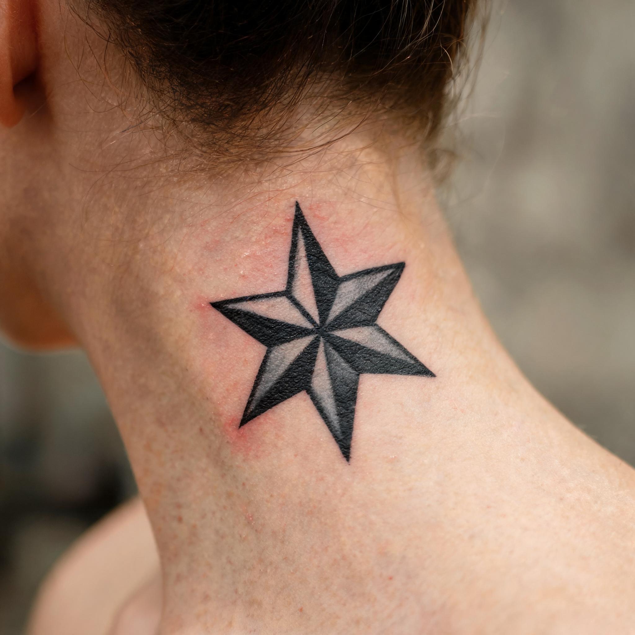 A nautical star tattoo image in colour realism, shown on the side of the neck against a clean neutral background.