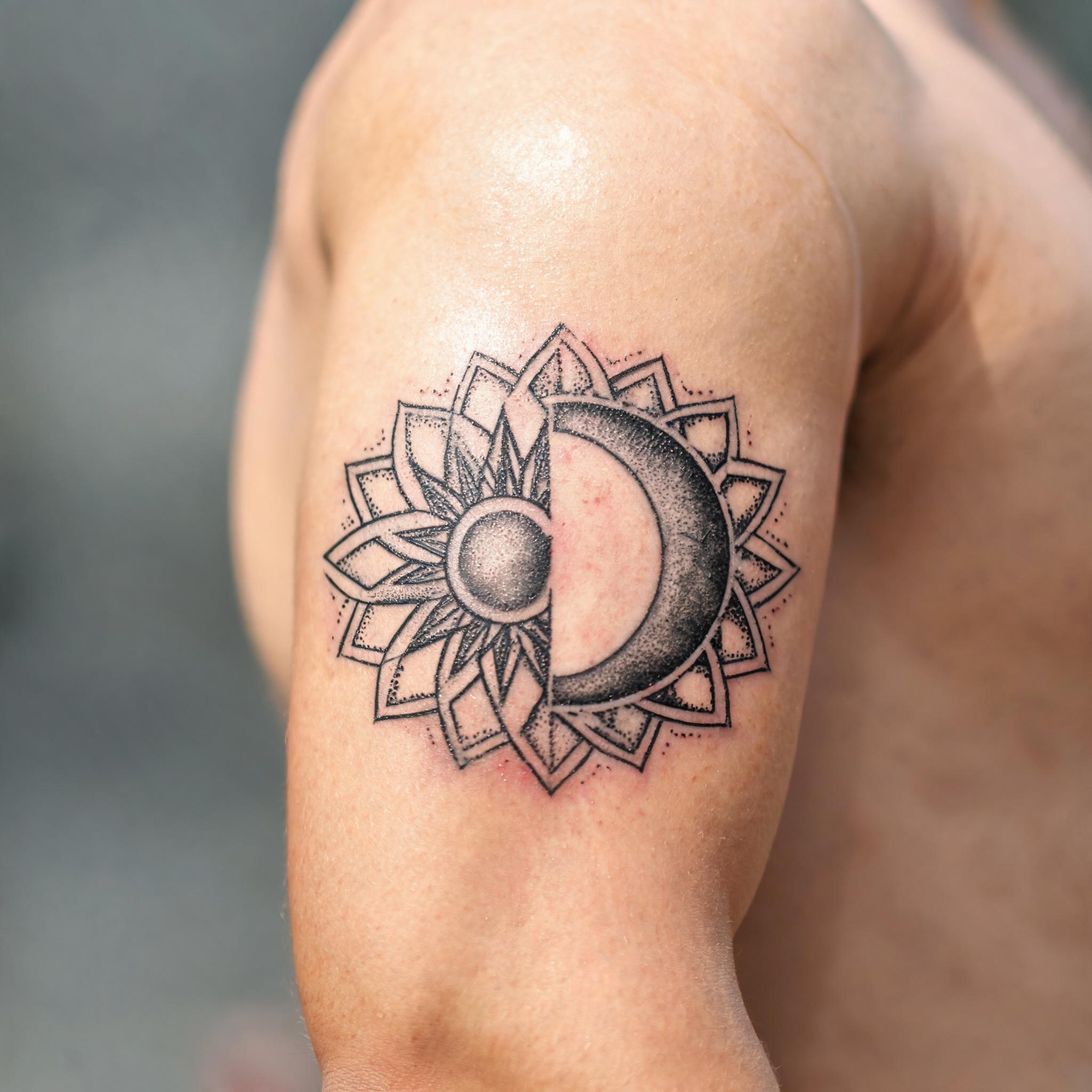 Geometric sun and moon tattoo images with dotwork mandala shading on an outer upper arm, shown as a black-and-grey tattoo on white.