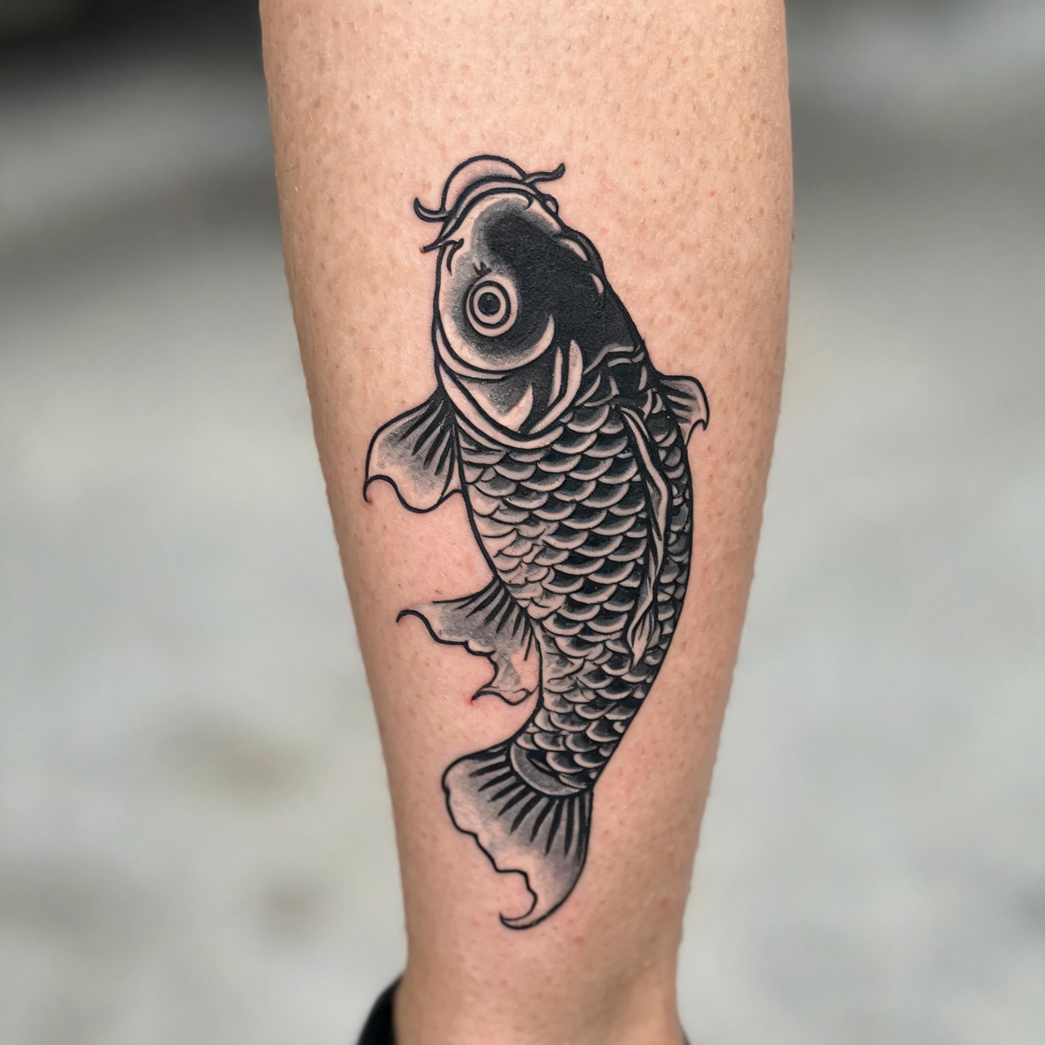 Black and grey American traditional tattoo of Japanese motifs on a shin, shown on real skin against a plain background.