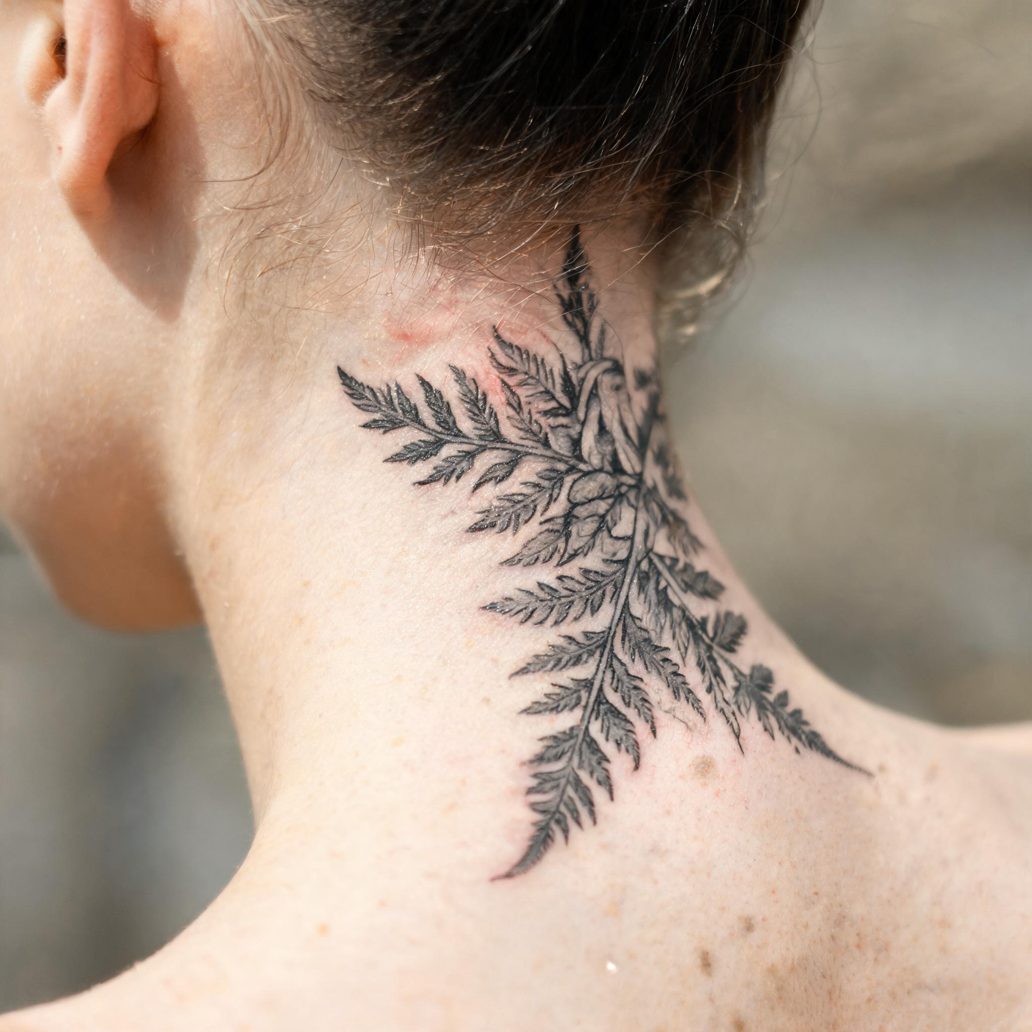Illustrative black-and-grey tattoo image of infected tattoo imagery on the nape and side of the neck, shown on real skin against a clean neutral background.