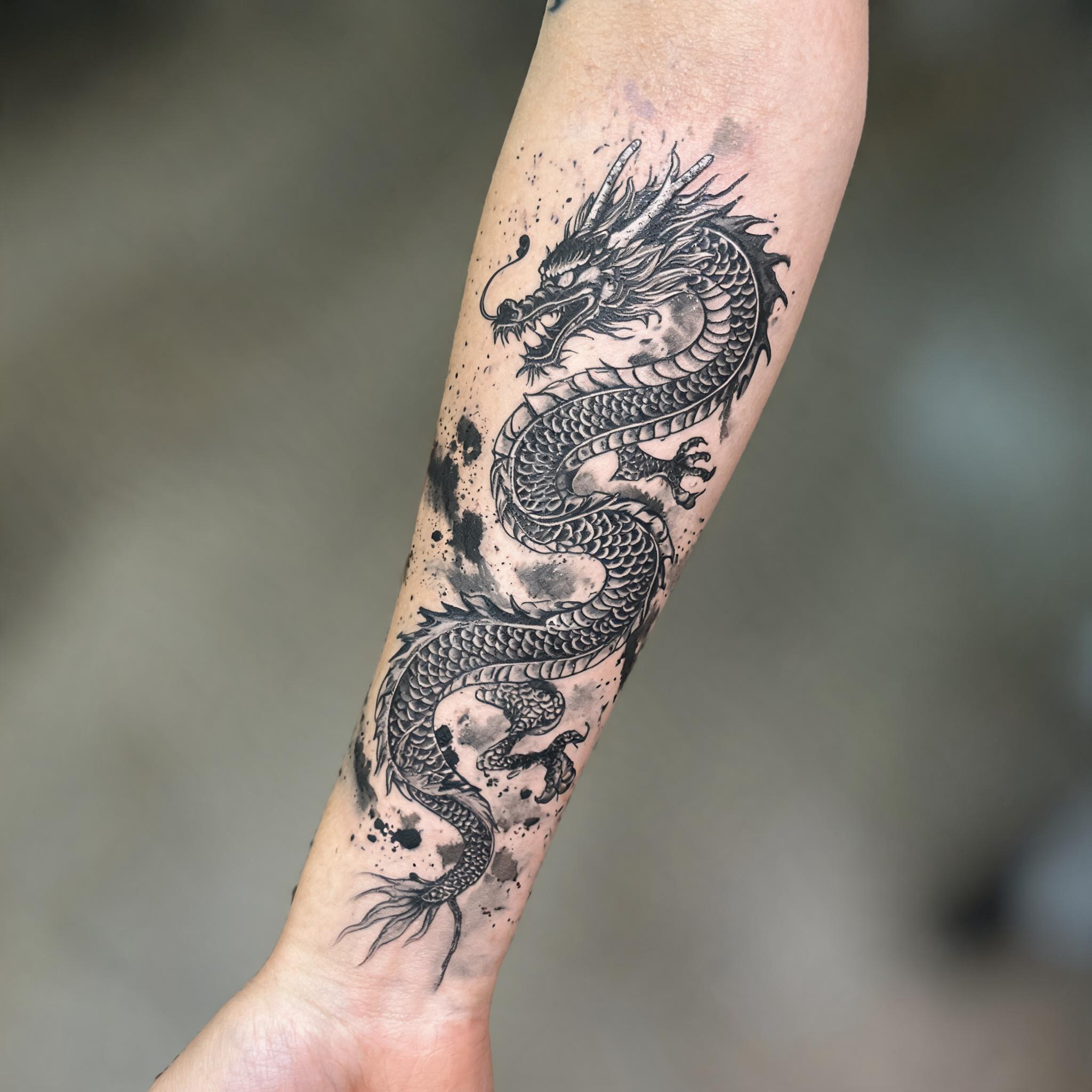 A Japanese dragon tattoo image in trash polka style on an inner forearm, black and red collage with brush strokes on a neutral background, shown as a tattoo photo.