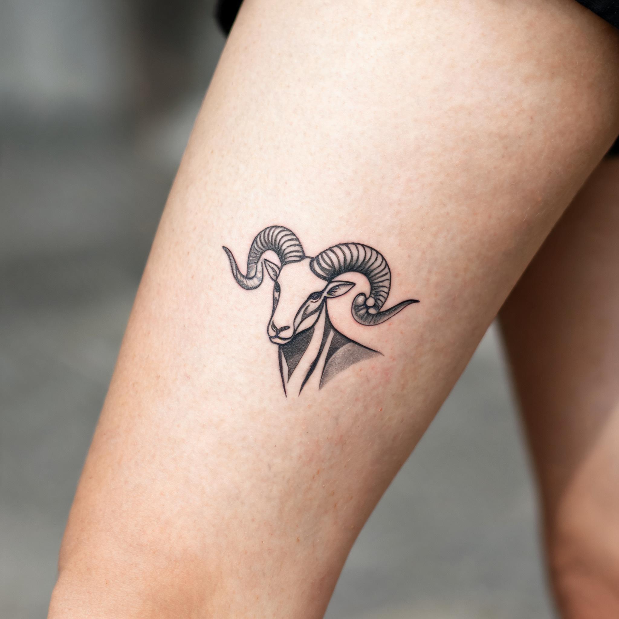 A minimalist Aries zodiac tattoo image on the outer thigh, shown in black and grey ink on realistic skin against a clean neutral background.