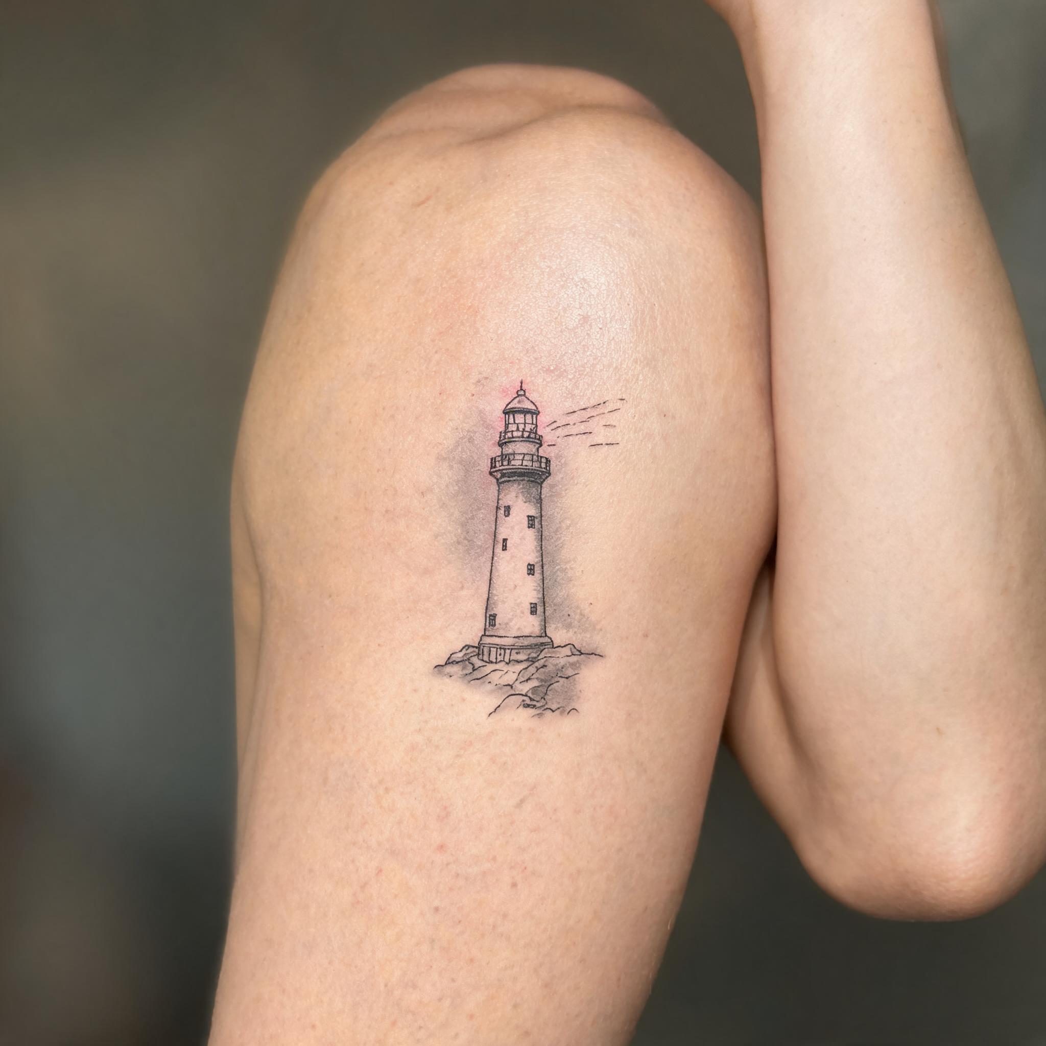 Fine line lighthouse tattoo design on the inner bicep, black and grey ink with delicate single needle lines shown as a tattoo image.