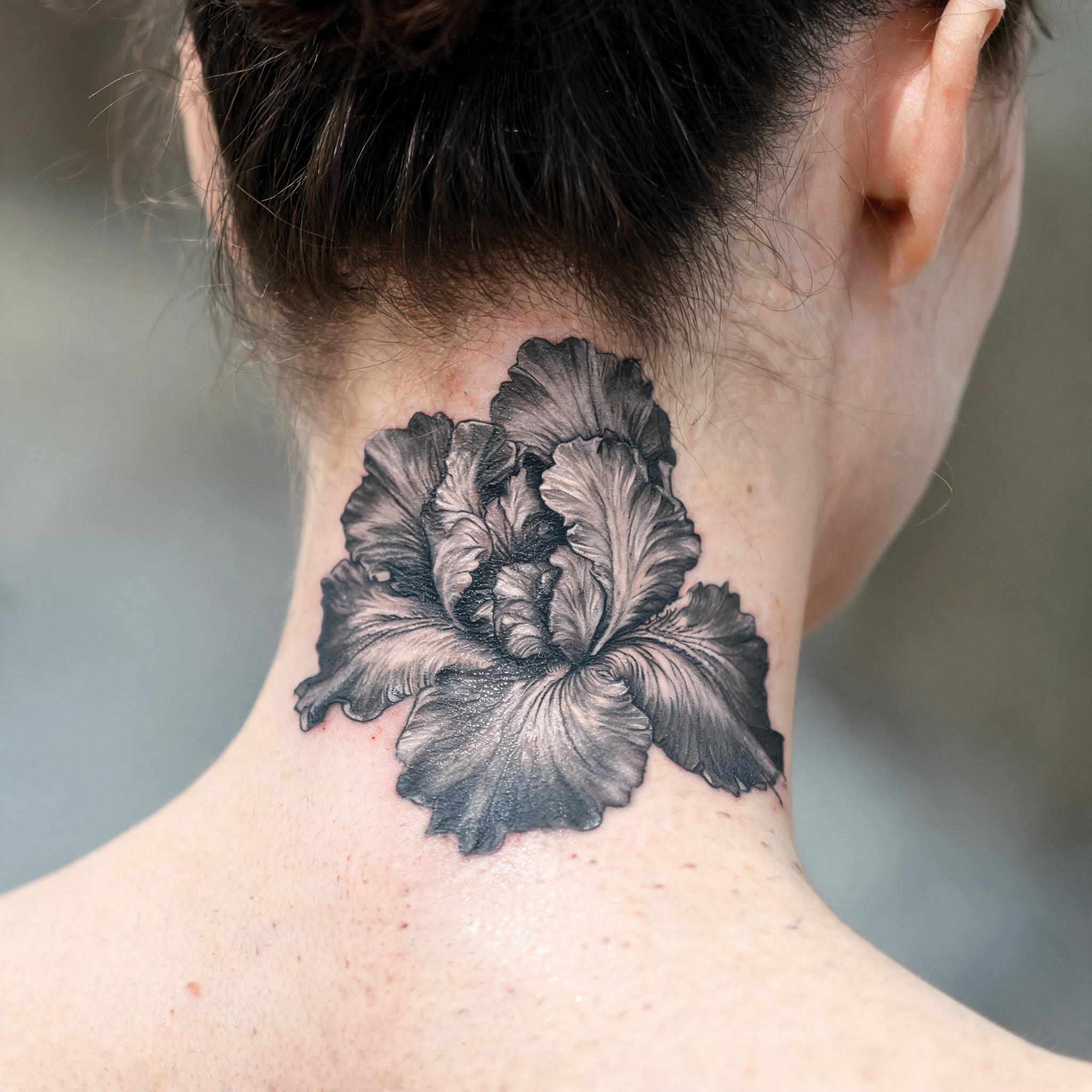 Black and grey realism iris flower tattoo design on the neck, shown on skin against a clean neutral background as a tattoo image.