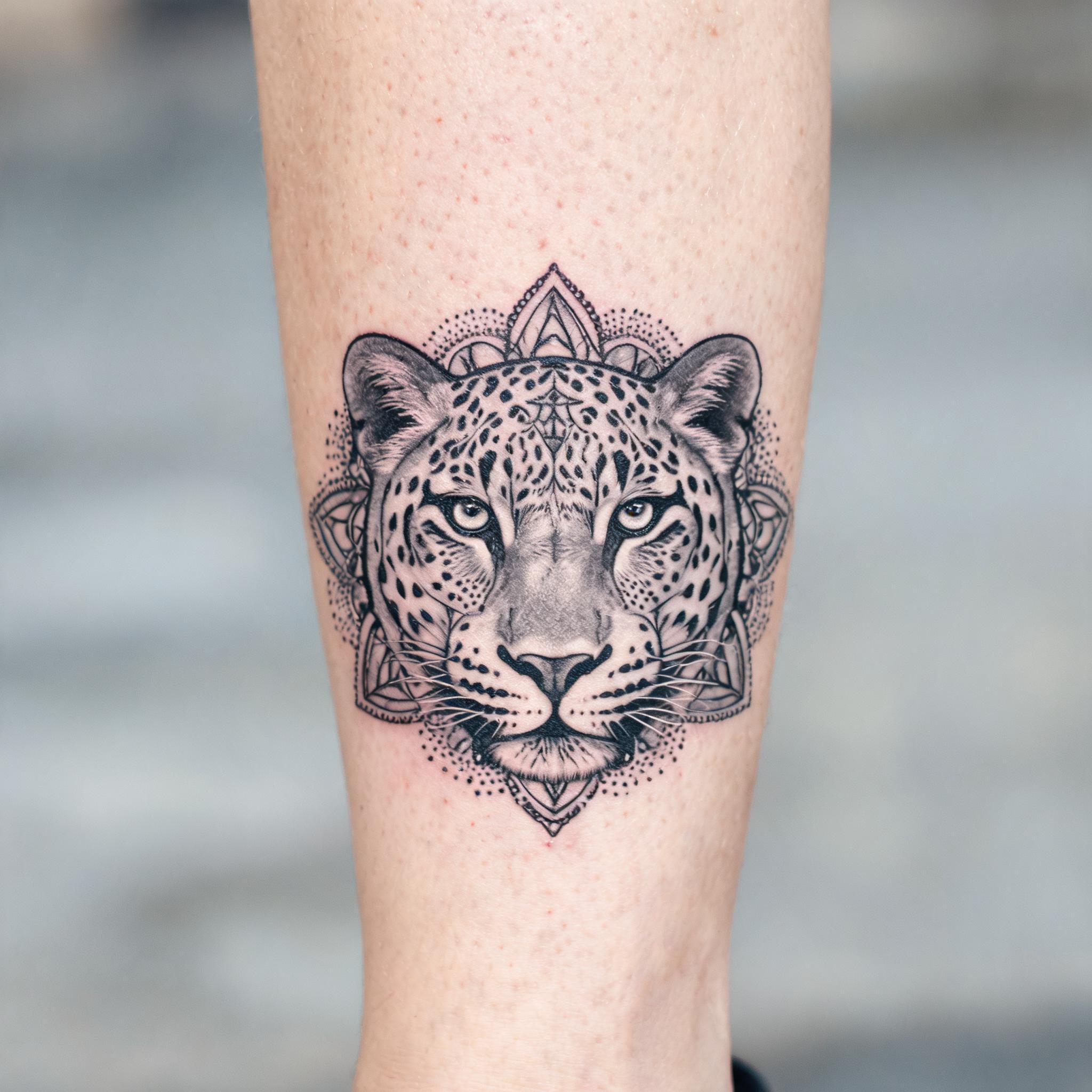 Geometric dotwork leopard face tattoo design in black and grey ink on a shin, shown on skin as a tattoo image.