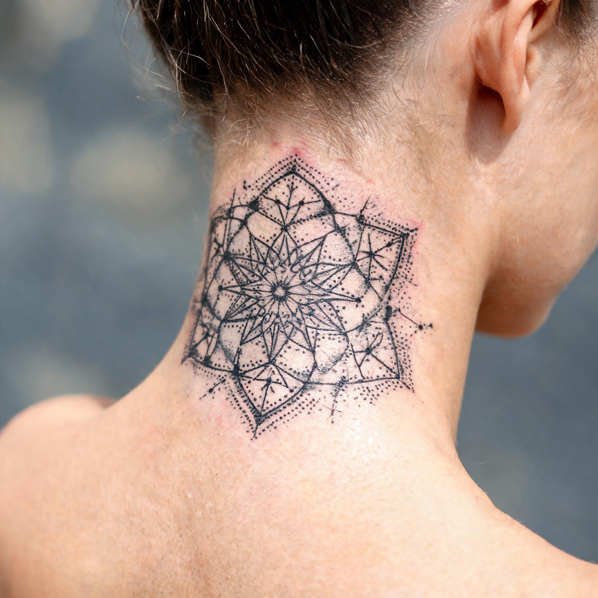 A black and grey celestial constellation tattoo design rendered in geometric dotwork on the nape of the neck, shown as a close-up tattoo image on skin.