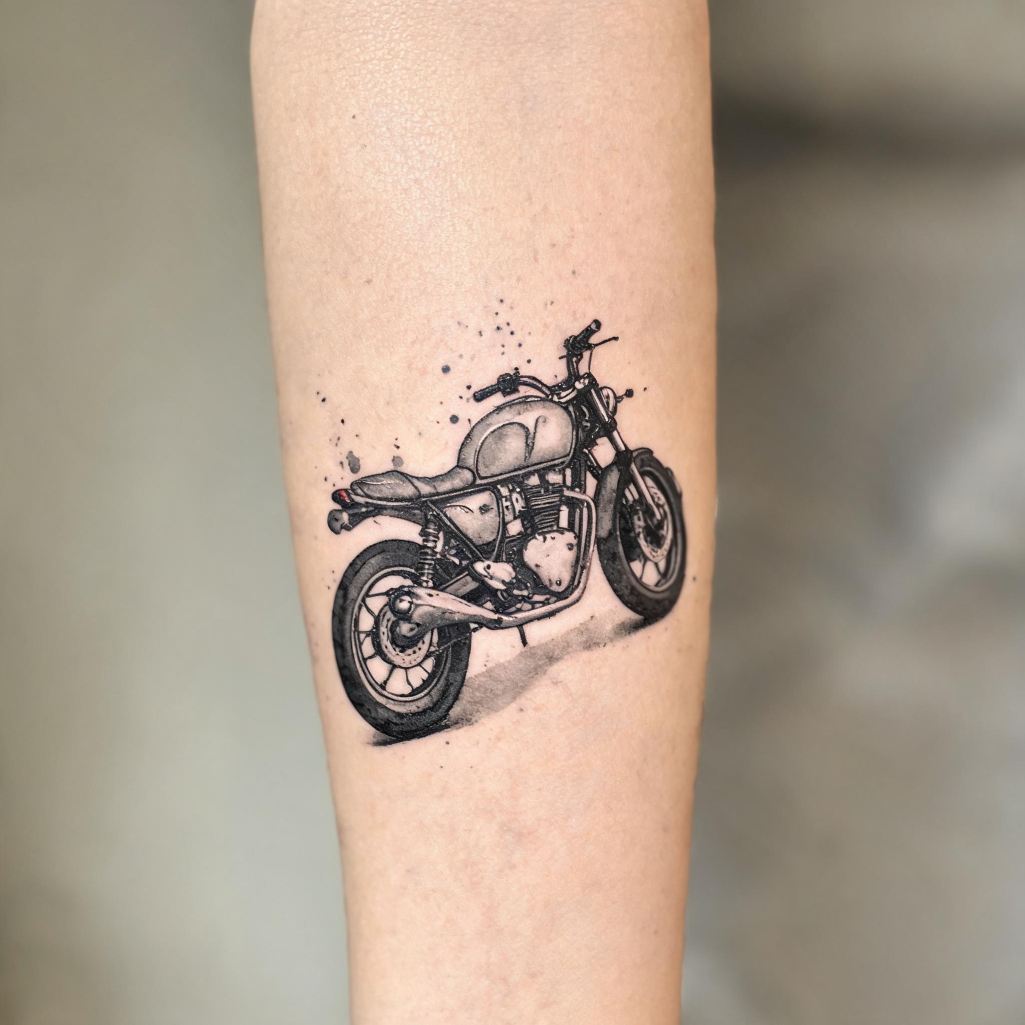A black and grey watercolor motorcycle tattoo design on a person's inner forearm, shown on a clean neutral background as a tattoo image.