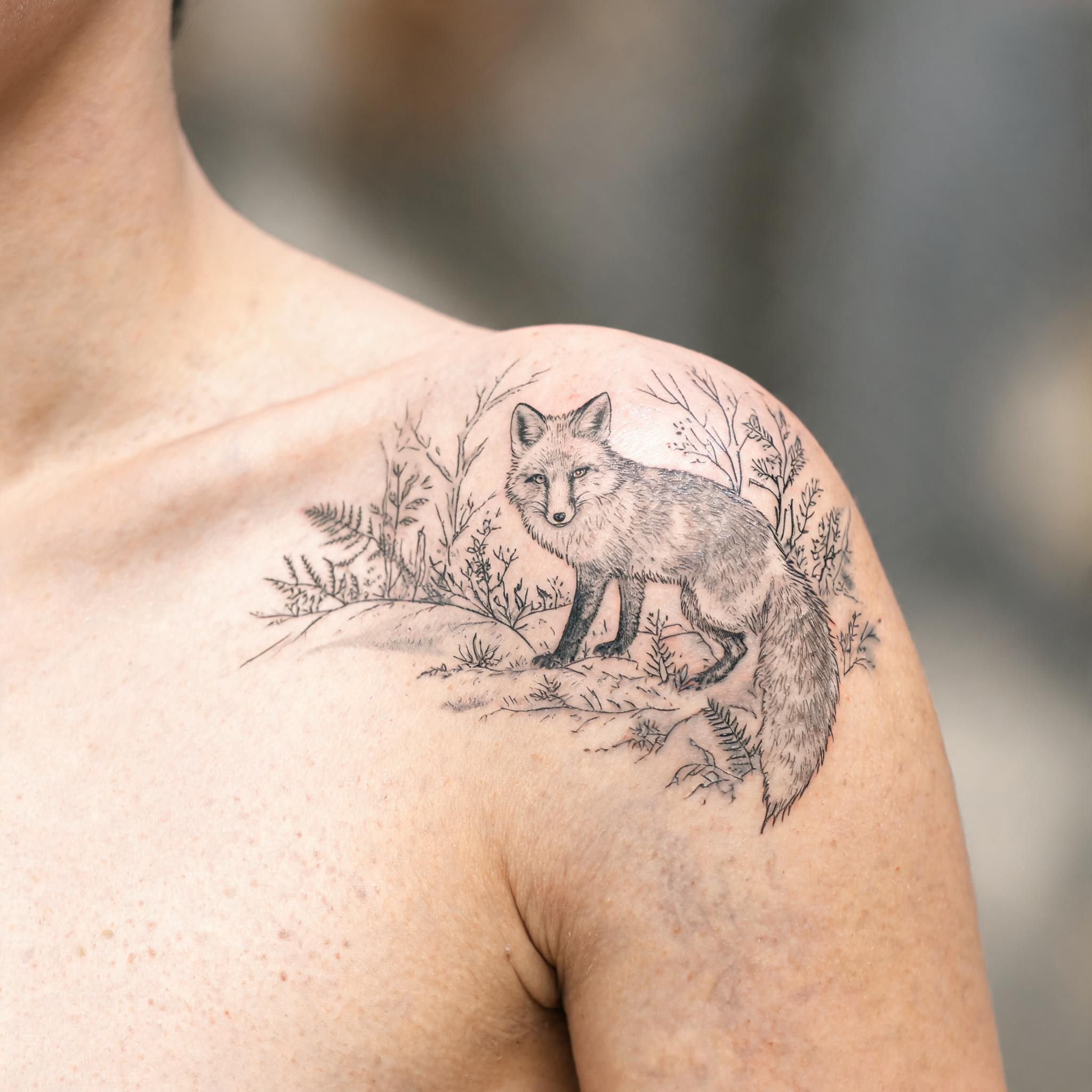 A fine line tattoo image of a red fox forest design on a shoulder cap, shown in black and grey with delicate single-needle lines against natural skin.